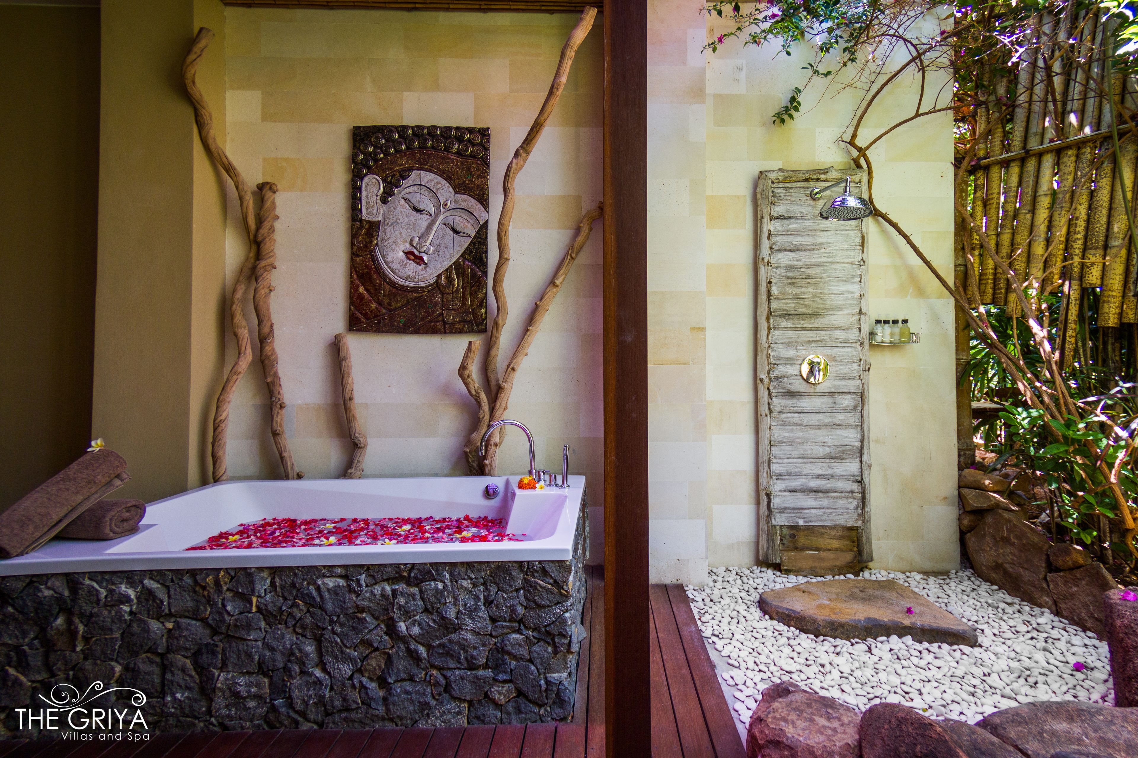 A spa room with a stone bathtub, a wooden door, and a wall-mounted artwork.