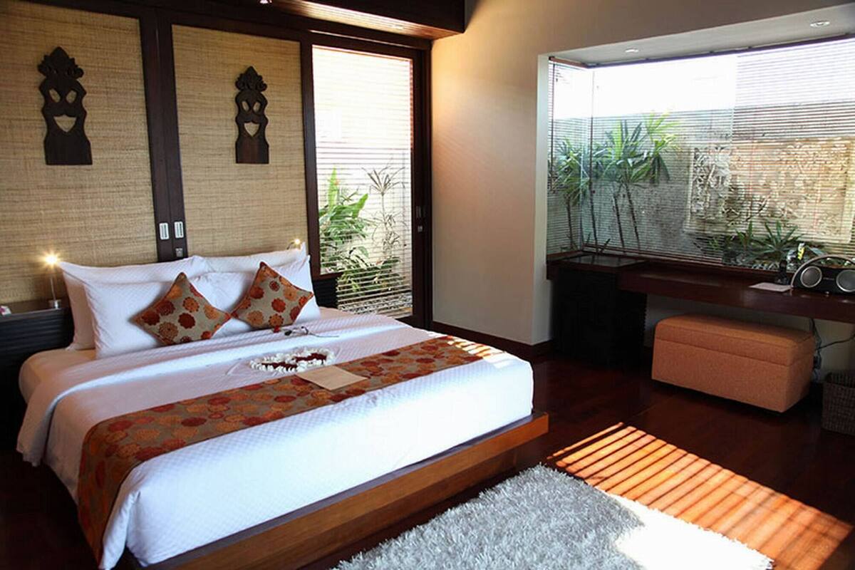 Un dormitorio con una cama grande, un escritorio y vistas a plantas a través de la ventana.