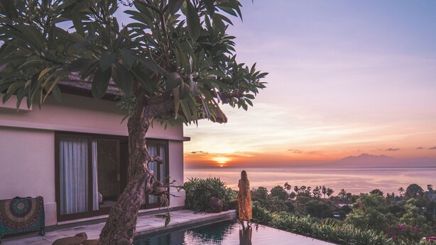 A modern house with a swimming pool, a tree, and a view of the sunset over the ocean. - The Griya Villas and Spa (Karangasem)