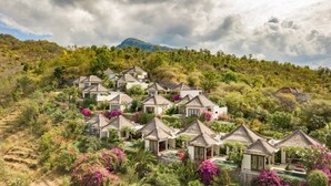 A hillside resort with multiple bungalow-style buildings, each with a thatched roof and surrounded by lush vegetation and a swimming pool. - The Griya Villas and Spa (Karangasem)