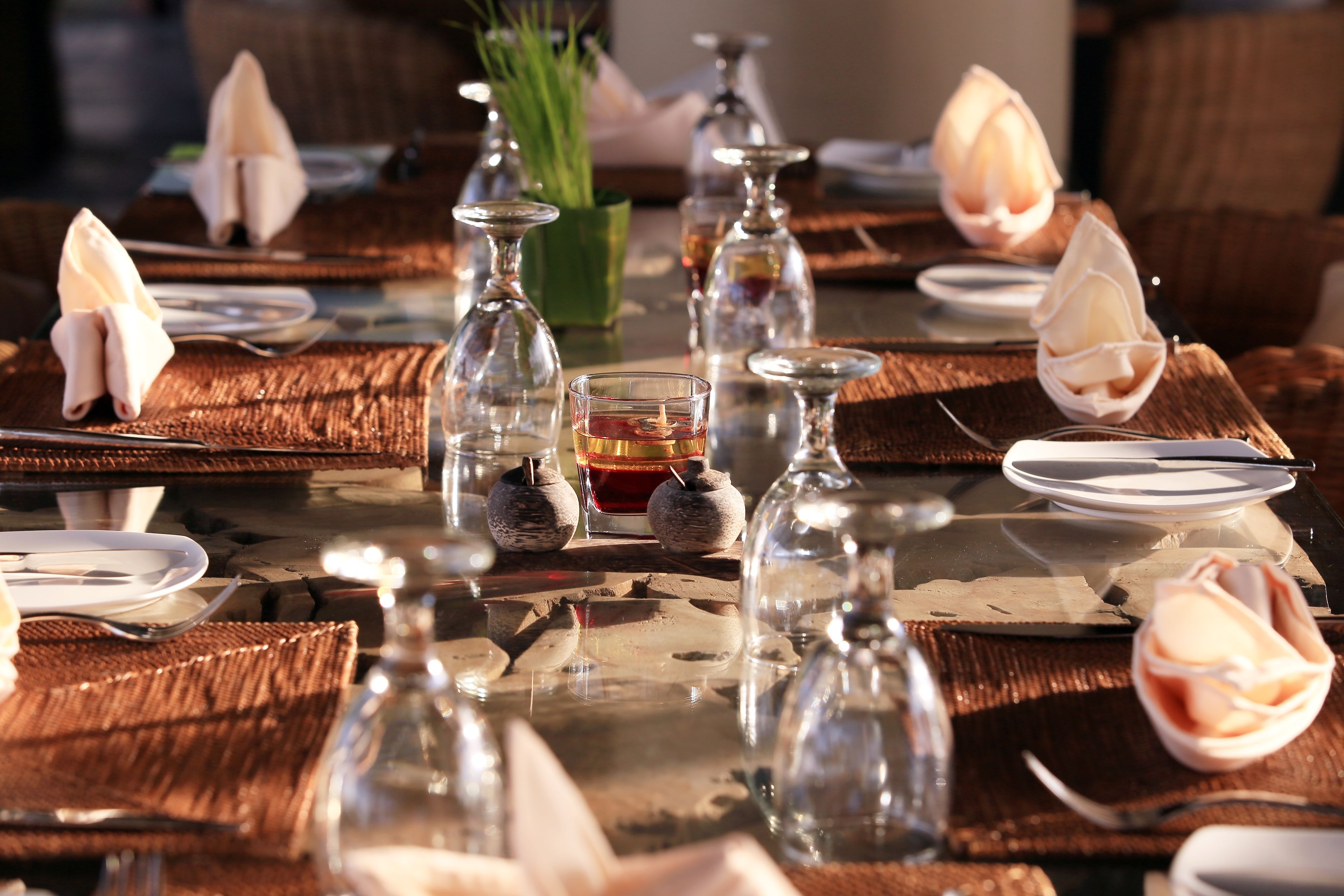 Uma mesa de jantar posta com copos, pratos e guardanapos.