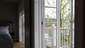 A bedroom with a bed, a bedside lamp, and a window leading to a balcony. - Kvosin Downtown Hotel (Reykjavik)