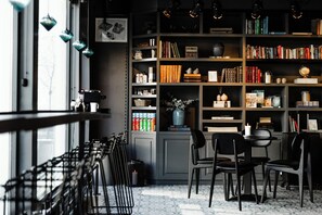 Een gezellige leeshoek met een boekenkast, stoelen en een koffieapparaat.