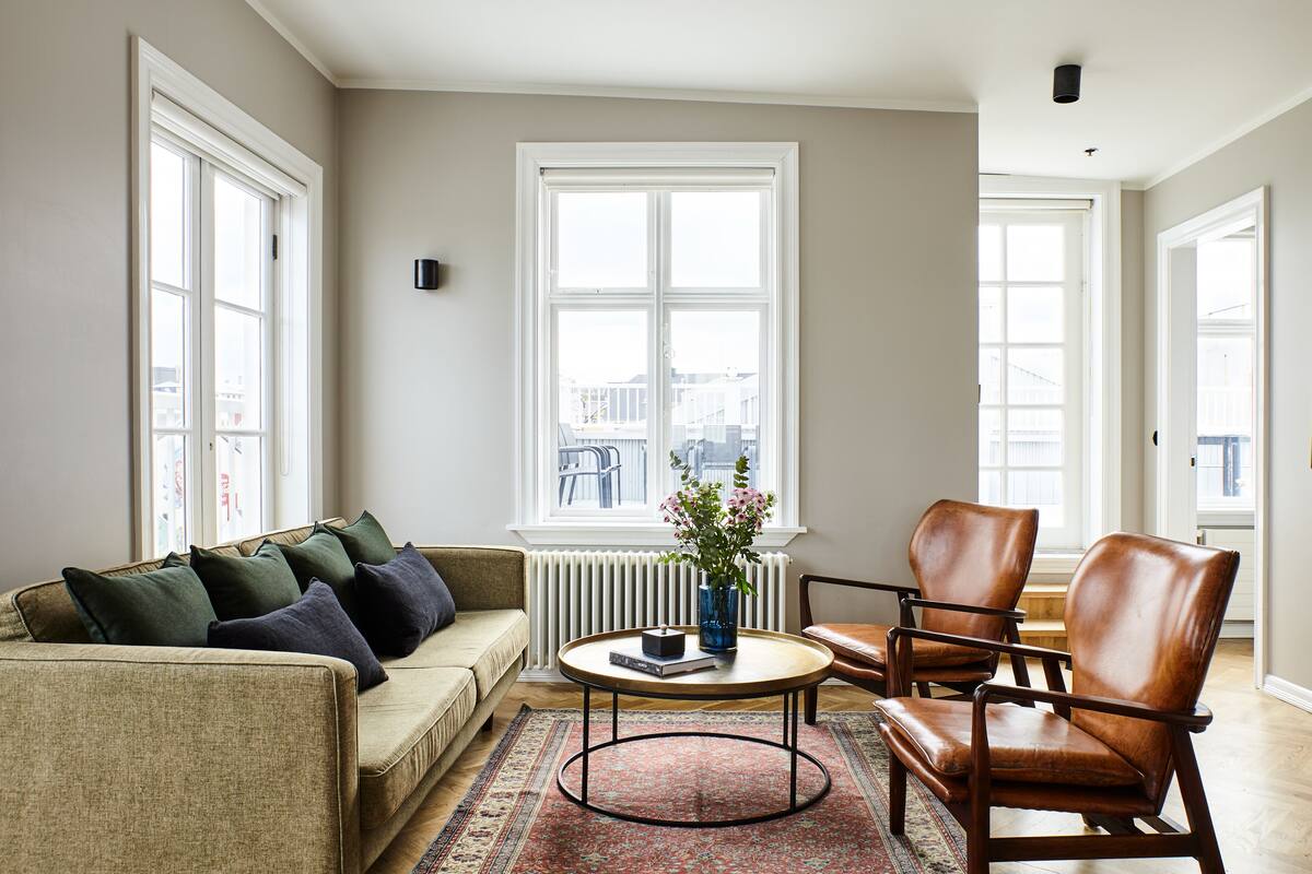 Un salon comprenant un canapé, une table basse et deux fauteuils en cuir.
