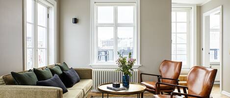 Una sala de estar con un sofá, una mesa de centro y dos sillones de cuero.
