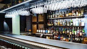 A bar area with a counter, multiple shelves of bottles, and hanging light fixtures. - Kvosin Downtown Hotel (Reykjavik)