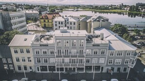 A hotel with a classic European architectural style, featuring a central courtyard and a view of a lake. - Kvosin Downtown Hotel (Reykjavik)