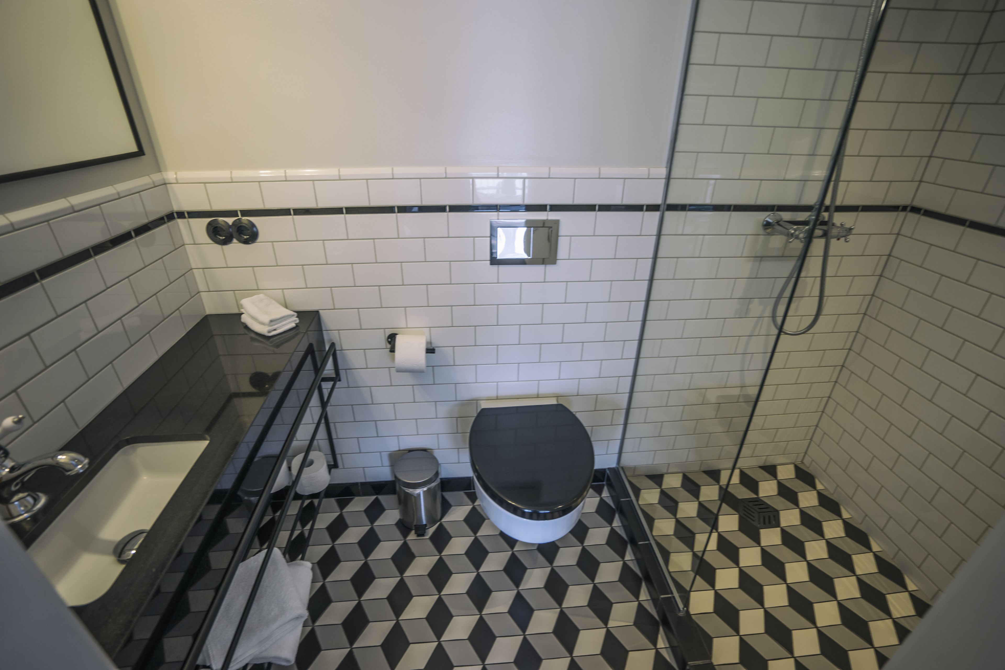 A bathroom with a black and white checkered floor, a white toilet, a bathtub, and a shower.
