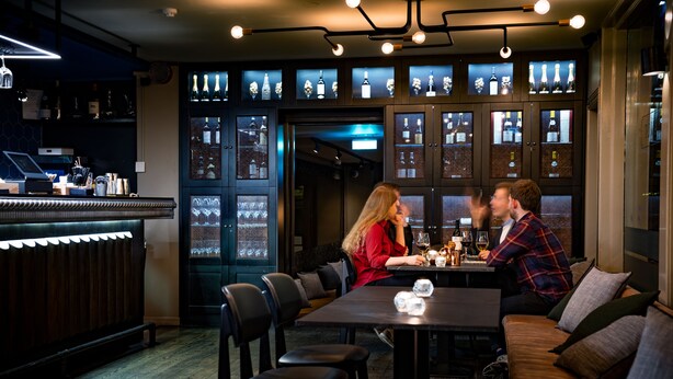 A bar area with a counter, seating, and a display of bottles. - Kvosin Downtown Hotel (Reykjavik)