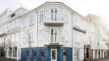 A corner building with a sign for 'KVOSIN HOTEL' and 'ALDAMOT' on the ground floor.