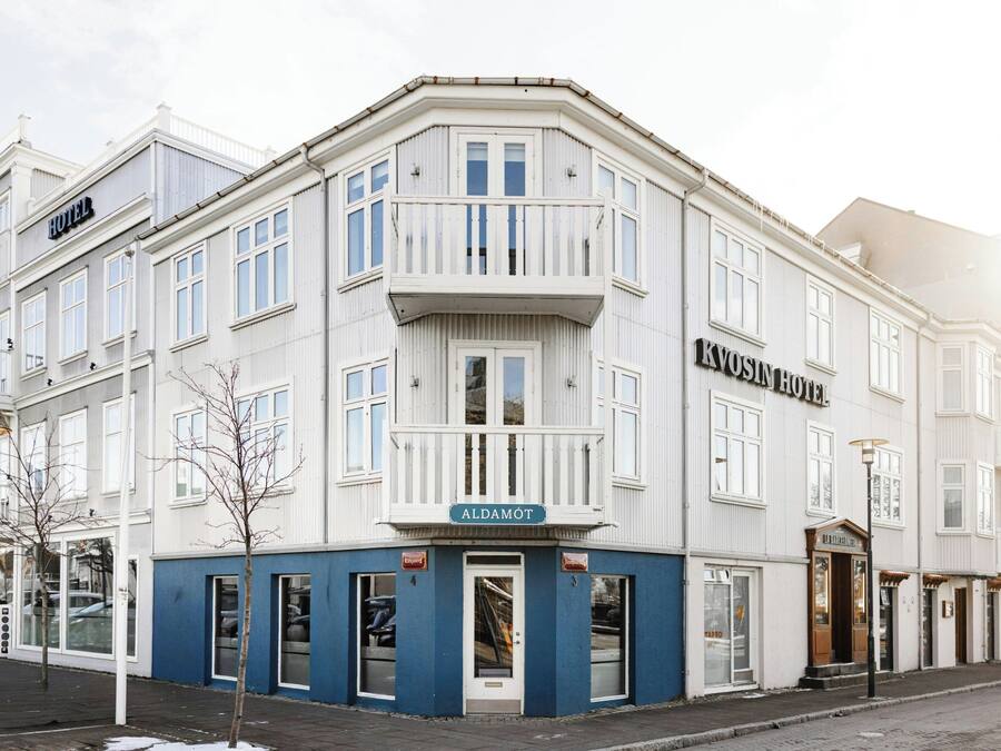 A corner building with a sign for 'KVOSIN HOTEL' and 'ALDAMOT' on the ground floor.