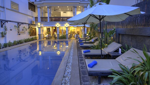 A hotel with a swimming pool, lounge chairs, and umbrellas. - Popular Boutique Hotel (Siem Reap)