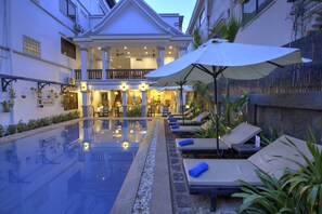 A hotel with a swimming pool, lounge chairs, and umbrellas. - Popular Boutique Hotel (Siem Reap)
