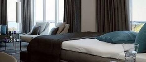 Ein modernes Hotelzimmer mit einem großen Bett, einer Couch und einem Esstisch.