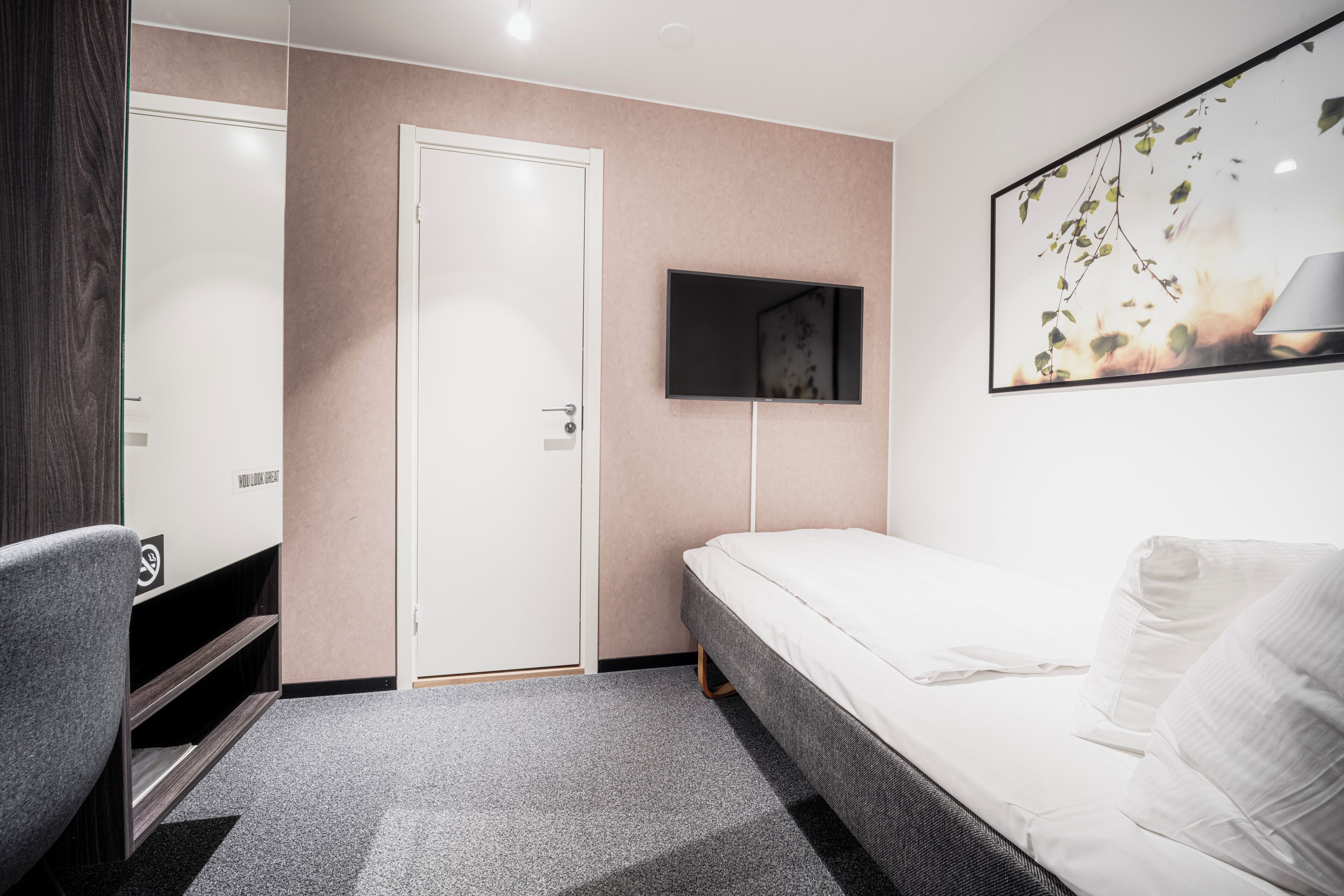 Un dormitorio moderno con cama, escritorio y televisor montado en la pared.