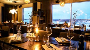Un restaurante con mesas dispuestas para comer, con velas y vistas a la ciudad.