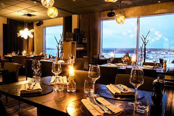 Un restaurante con mesas dispuestas para comer, con velas y vistas a la ciudad.
