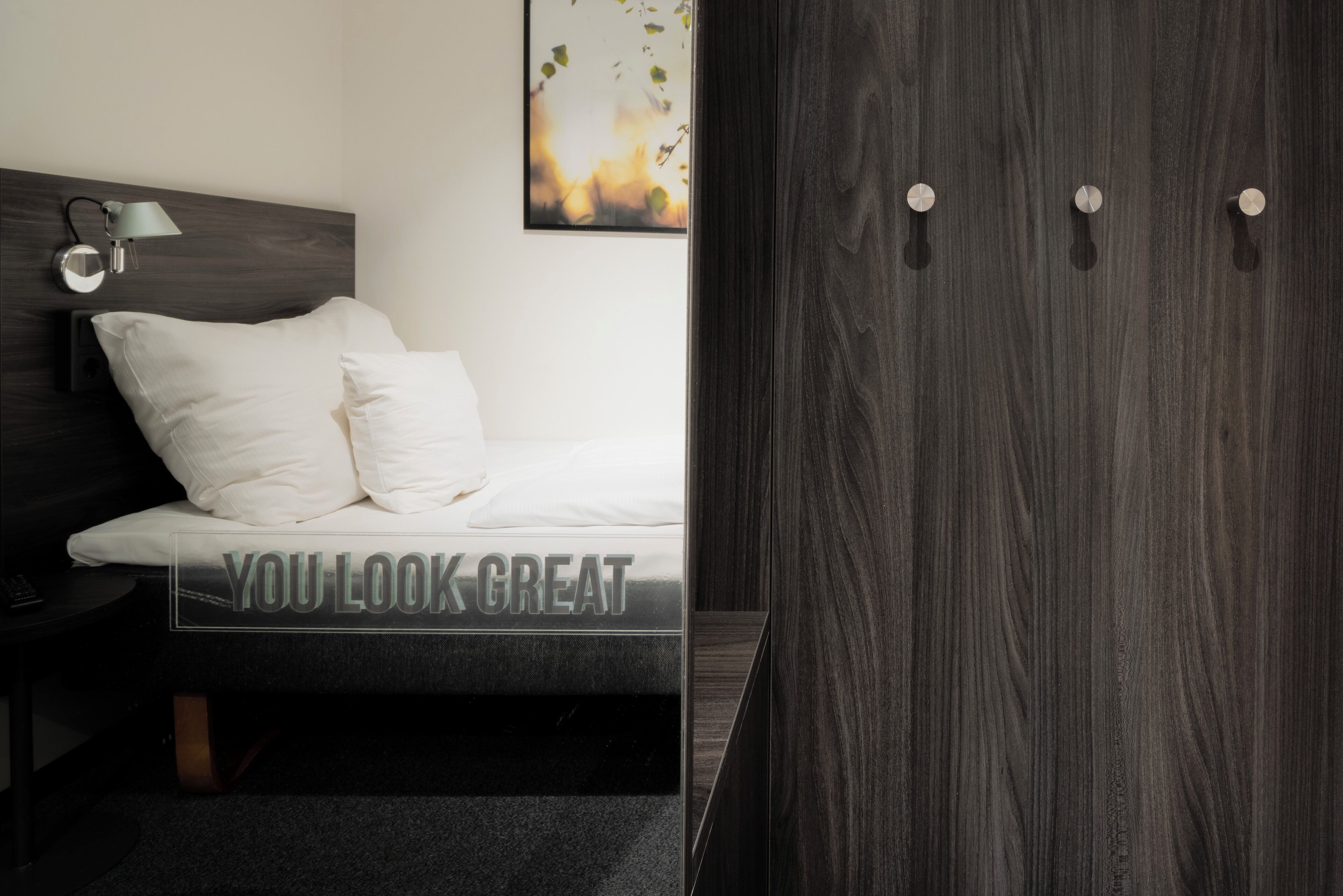 Un dormitorio moderno con cama, lámpara de noche y armario.