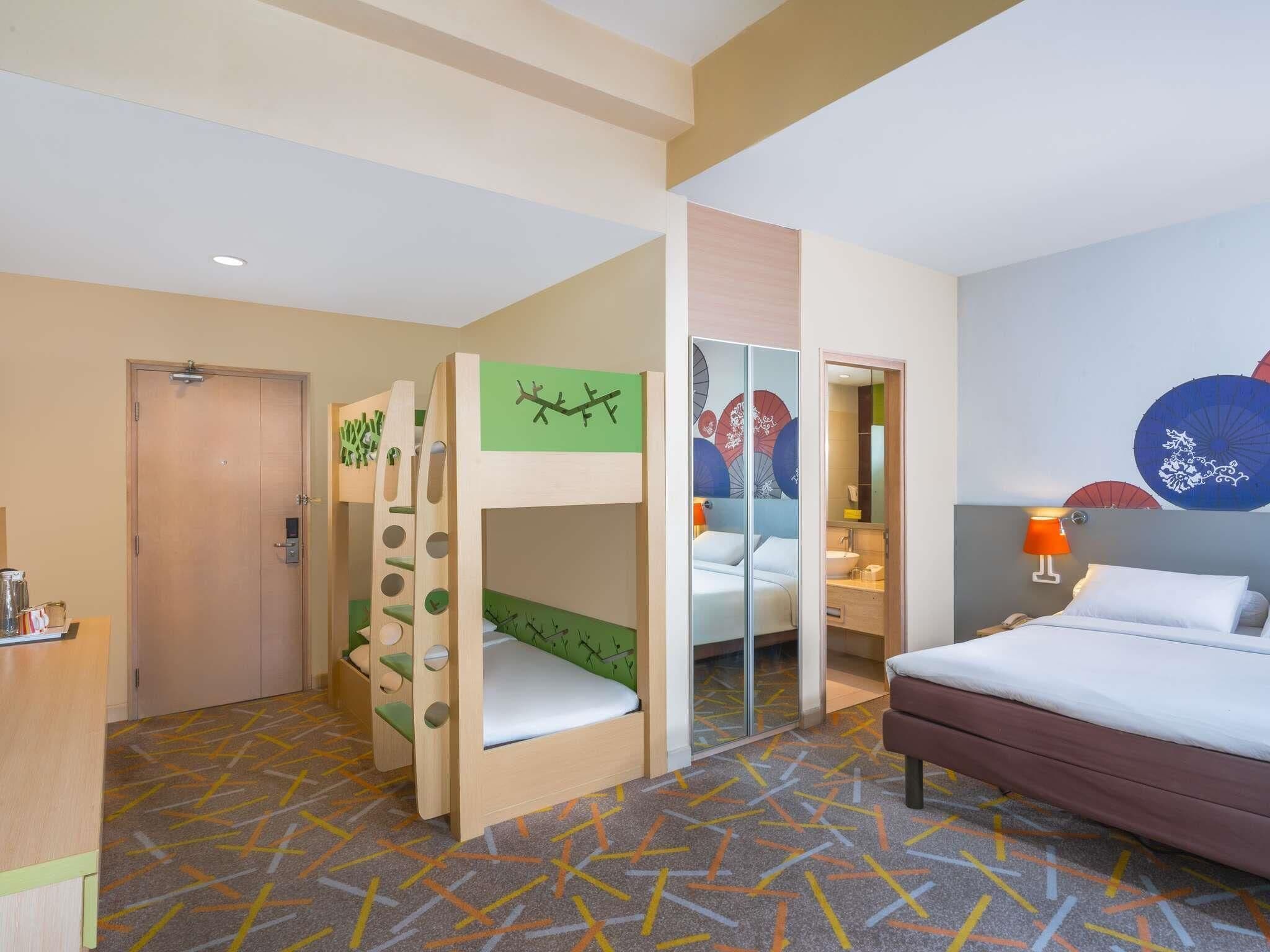 A hotel room with bunk beds, a bathroom, and a bed.