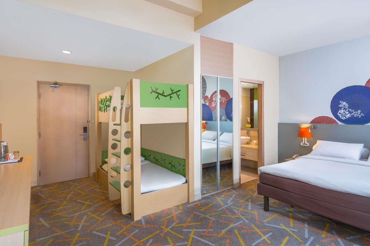 A hotel room with bunk beds, a bathroom, and a bed.