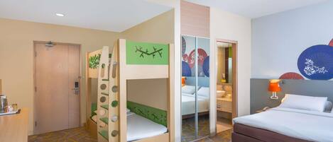 A hotel room with bunk beds, a single bed, a bathroom with a mirror, and a wall with decorative umbrellas.
