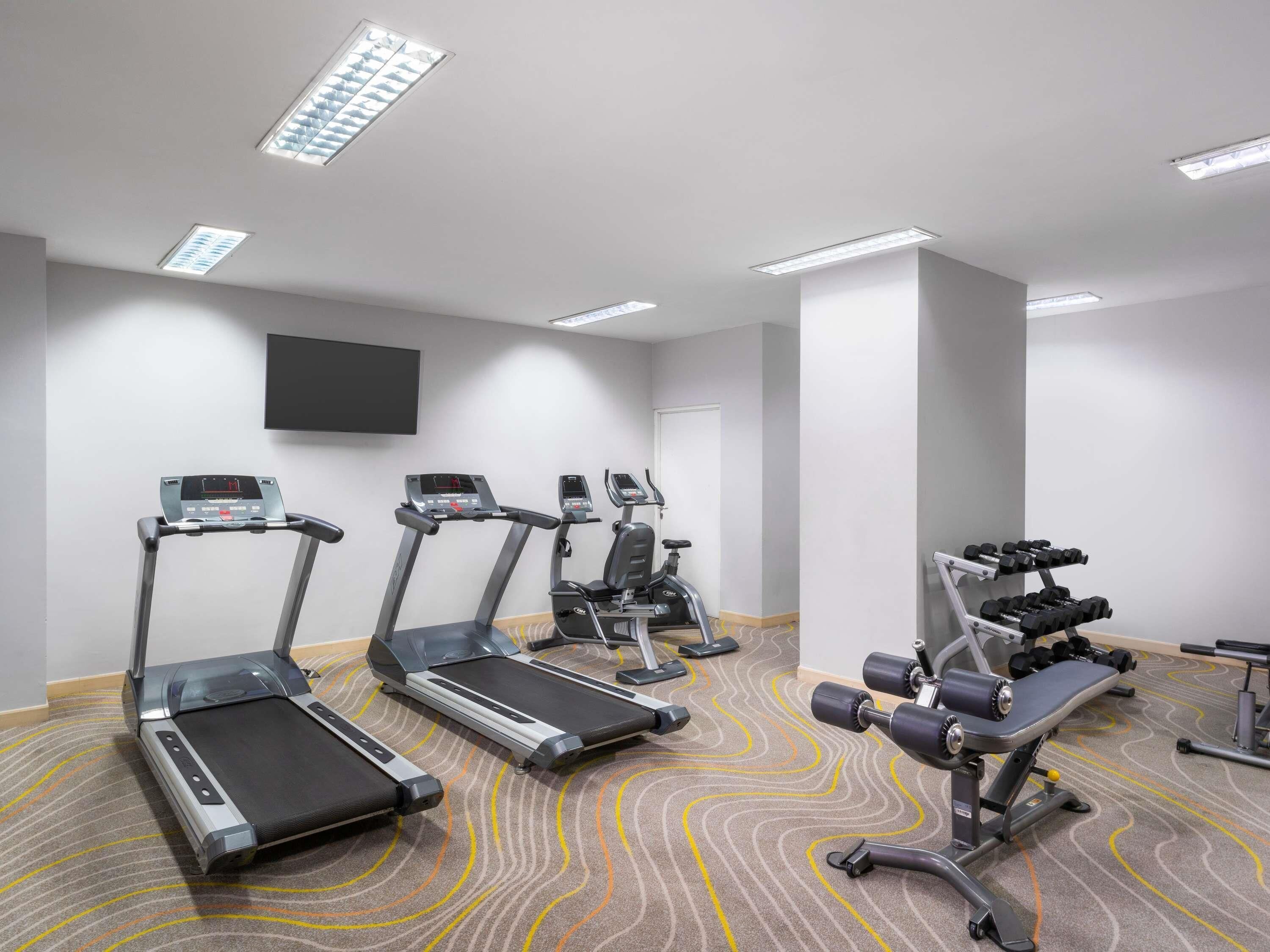 A gym with treadmills, elliptical machines, and weightlifting equipment.