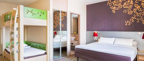 A hotel room with a bunk bed, a single bed, a mirror, a bathroom with a sink, and a patterned carpet.