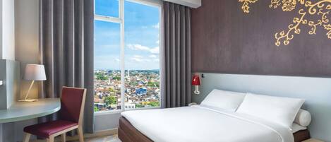 A hotel room with a large bed, a desk with a chair, a nightstand, and a view of a cityscape through a large window.
