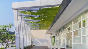 A modern building with a covered walkway, large windows, and a clear sky. - Ibis Styles Malang (Malang)