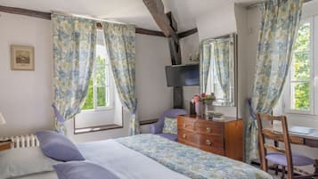 A bedroom with a bed, dresser, chair, and a desk with a mirror.