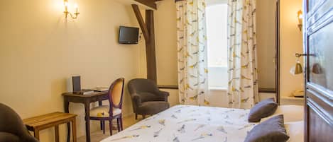 Habitación de hotel con cama, escritorio, silla y televisor.