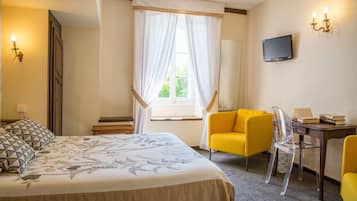Una camera d'albergo con un letto, una scrivania, una sedia, una televisione e una finestra con tende.