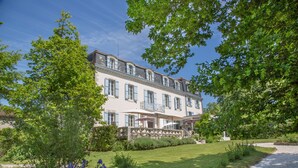 A large, multi-story building with a symmetrical facade, a central entrance with a staircase, and a well-maintained garden with a gravel path. - Château Bellevue (Cazaubon)