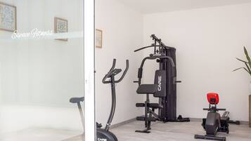 Un gimnasio en casa con bicicleta estática, elíptica y máquina de pesas.