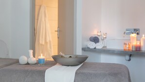 A spa room with a massage table, candles, and a bowl of herbs. - Château Bellevue (Cazaubon)