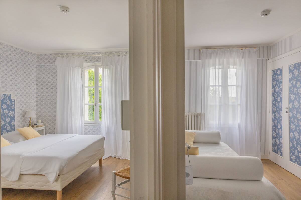 A bedroom with a bed, bedside table, and a window with curtains.