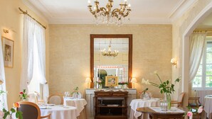 A dining area with multiple tables, a chandelier, and a large mirror. - Château Bellevue (Cazaubon)