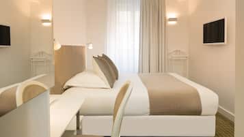 Een hotelkamer met een bed, bureau, stoel, televisie en een raam met gordijnen.