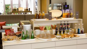 A buffet setup with various food items, beverages, and a coffee machine. - Hôtel Mistral (Paris)