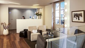A hotel lobby with a reception desk, seating area, and a glass partition. - Hôtel Mistral (Paris)
