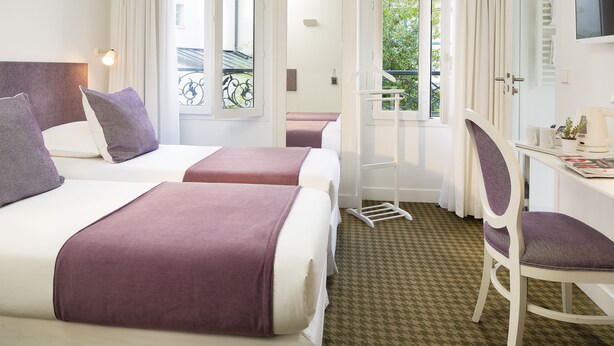 A hotel room with two beds, a desk, and a chair. - Hôtel Mistral (Paris)