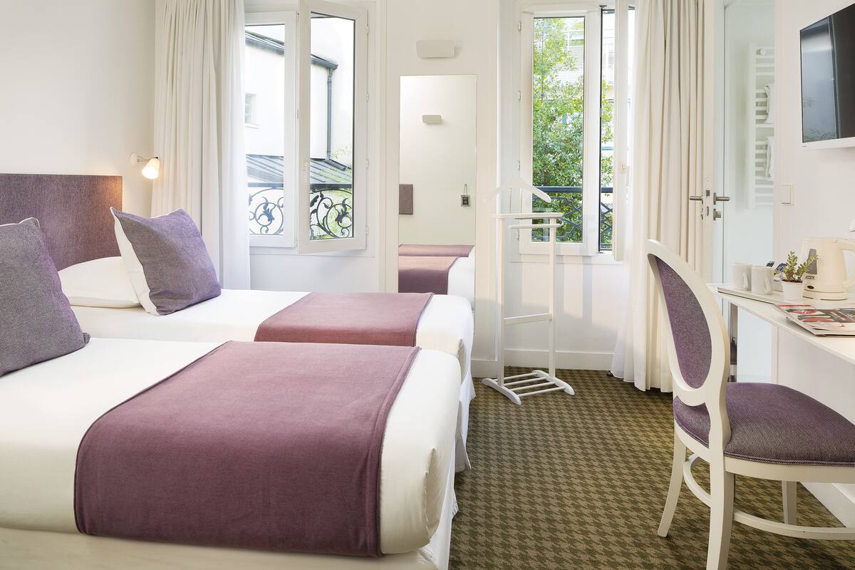 Habitación de hotel con dos camas, un escritorio y una silla.