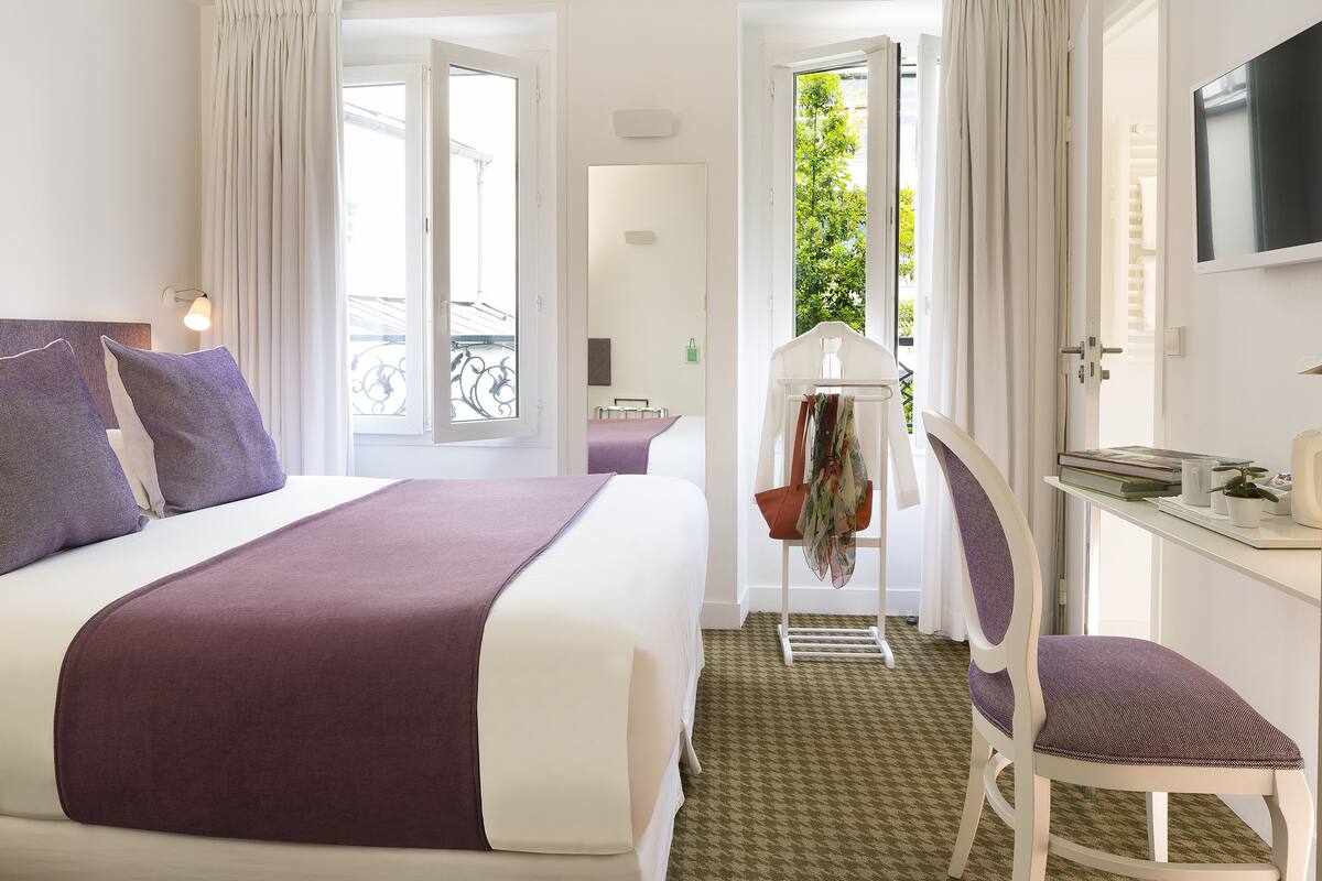 Una habitación de hotel con cama, una silla, un escritorio y televisor.
