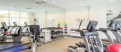A gym with treadmills, elliptical machines, and free weights.