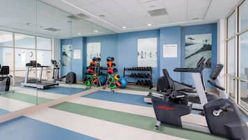 Een fitnessruimte met loopbanden, krachtapparaten en fitnessballen.