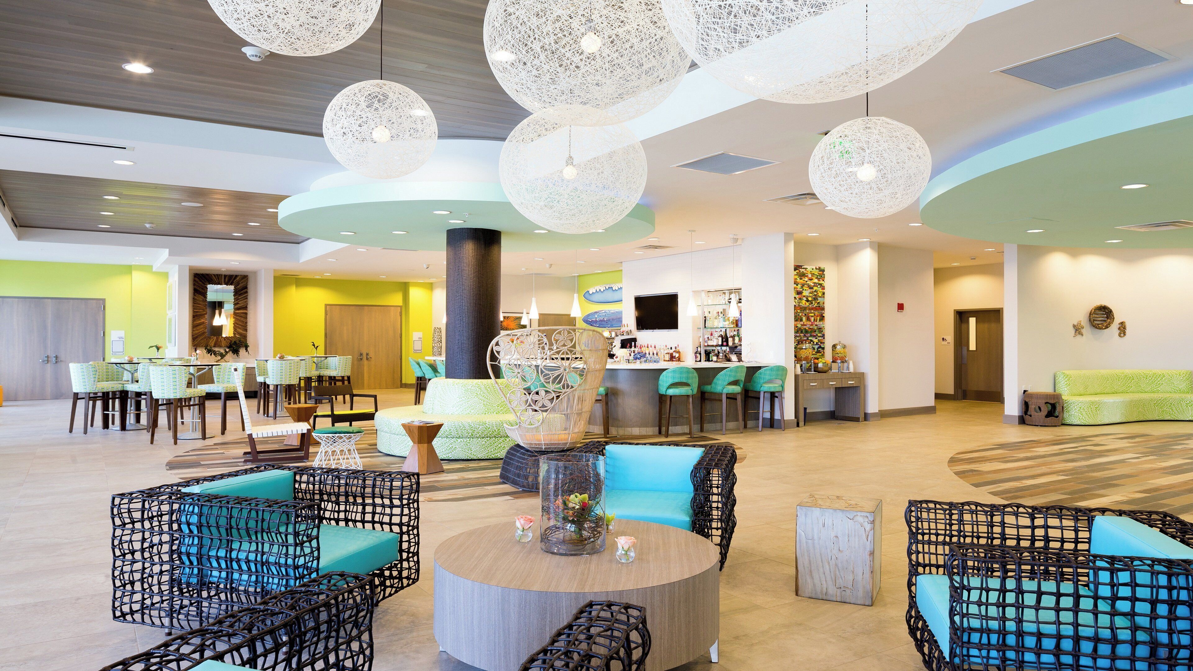 A hotel lobby with a bar area, seating arrangements, and a large decorative light fixture.