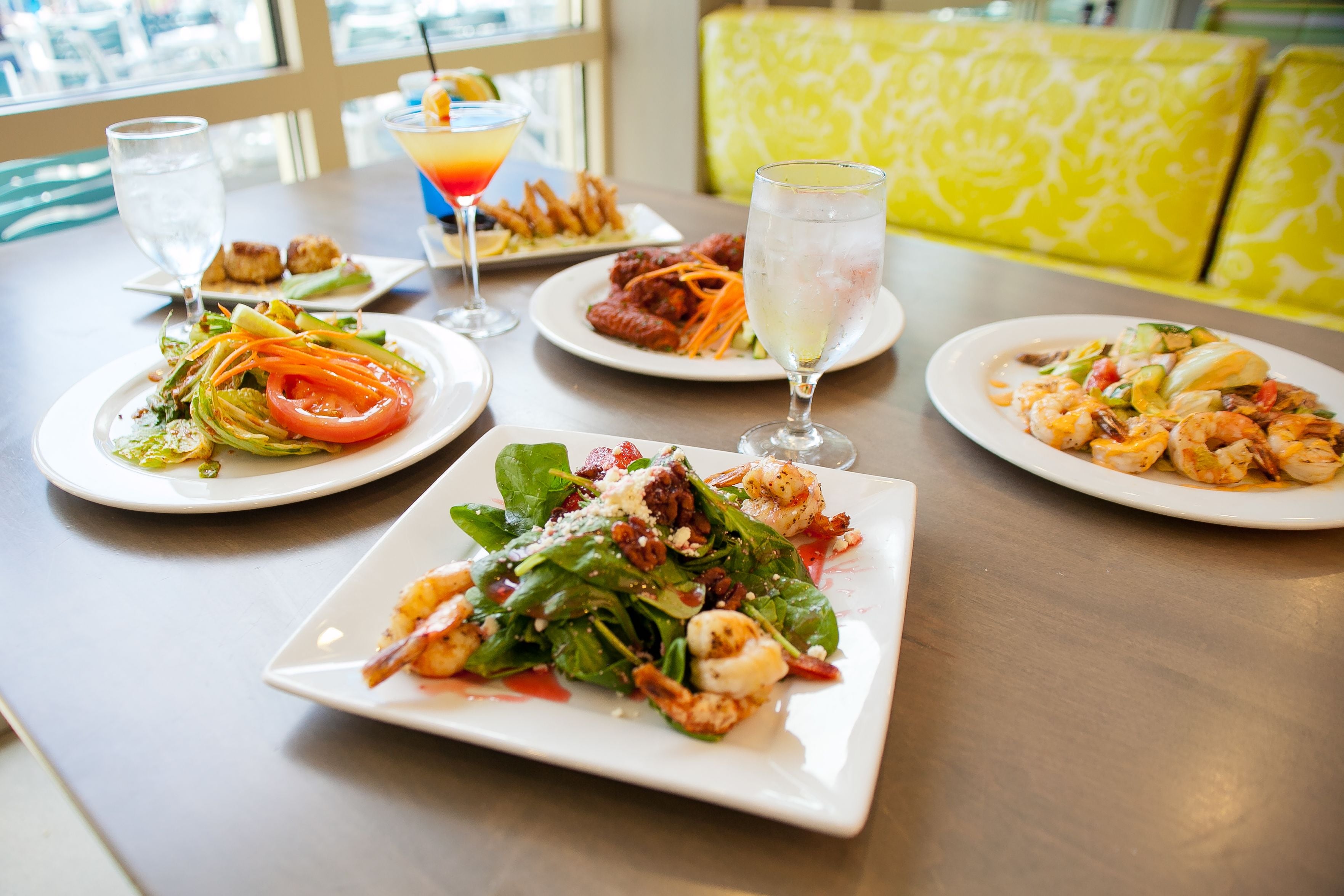 A dining table with various plates of food and drinks.