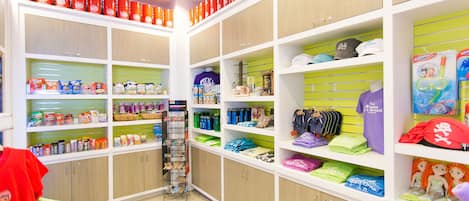 Una tienda minorista muy iluminada con estantes llenos de diversos productos, como aperitivos, bebidas y ropa infantil.