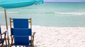 A beach scene with a turquoise umbrella and a blue beach chair. - Holiday Inn Resort Fort Walton Beach by IHG (Fort Walton Beach)