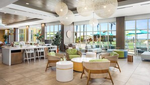 A spacious lobby with a bar area, seating with a view of the beach, and large windows. - Holiday Inn Resort Fort Walton Beach by IHG (Fort Walton Beach)